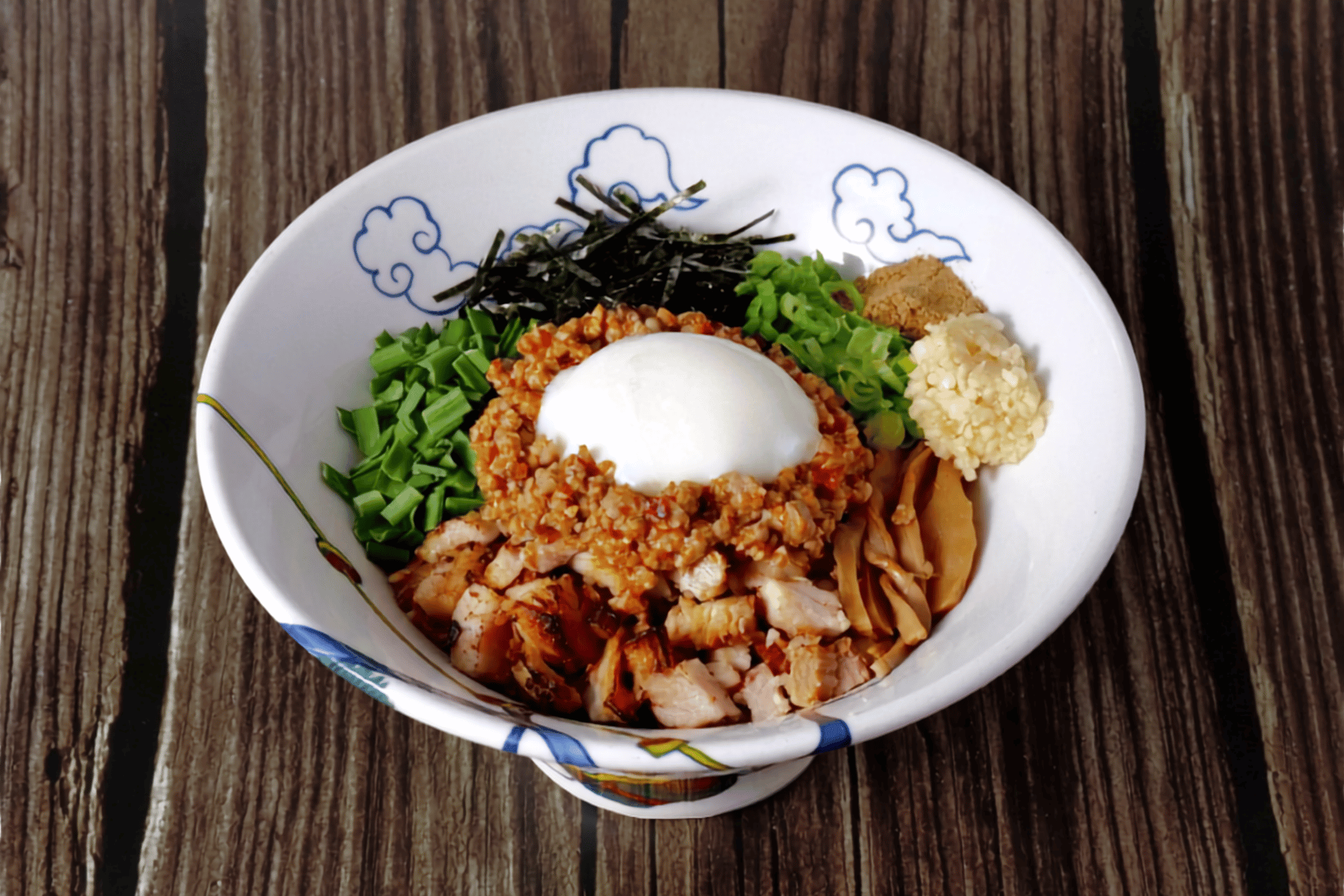 Toppings on RAMEN RAIJIN Spicy Taiwanese Mazesoba — spicy Taiwanese minced pork, diced pork chashu, chives, green onions, bamboo shoots, nori seaweed, chopped garlic, dried fish powder and a poached egg