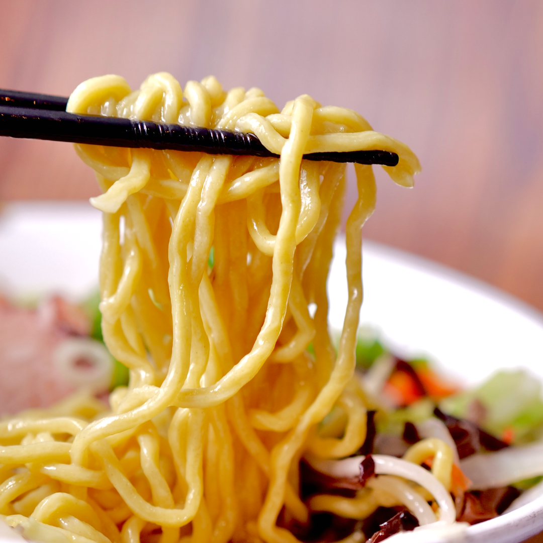 Fresh ramen noodles lifted from a bowl of RAMEN RAIJIN Frozen Shio Tanmen